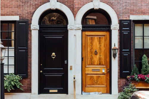 Two front doors side by side, one painted black and one of natural wood